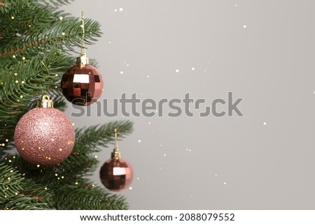 Minimal composition with pink glittering Christmas decorations. New Year ornaments in front of gray background with place for text.