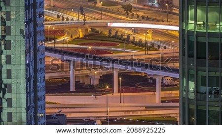 Aerial view of big intersection with many transports in traffic night timelapse in Dubai Downtown, Dubai, United Arab Emirates. Top view between skyscrapers with streetlights and overpass