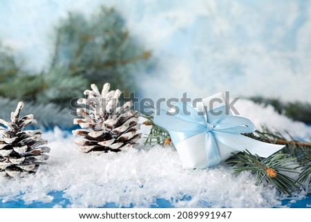 Christmas gift, cones and fir branches on snow, closeup