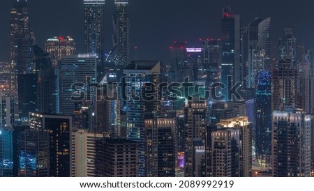 Skyline with modern architecture of Dubai business bay top of illuminated towers night timelapse. Aerial view with construction site