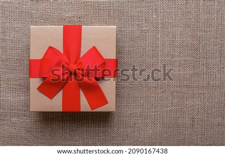 A beautiful gift box lies on a burlap background.