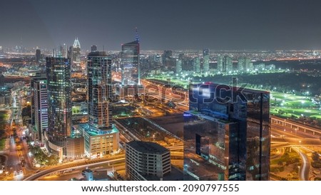 Moon rising over media city and al barsha heights district area night aerial timelapse from Dubai marina. Towers and skyscrapers with traffic on a highway from above