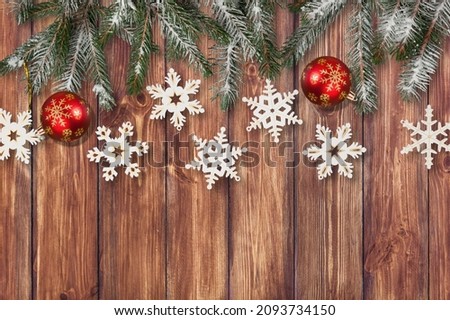 Fir branch with Christmas decoration on a painted wooden background.