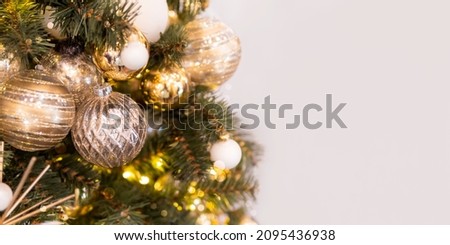 Christmas tree with beige decorations. Fir tree decorated with light bulbs and balls for New Year celebration. Banner with copy space.