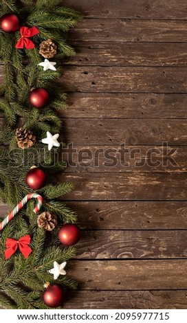 Preparing a nice Christmas wooden background with conifer branches and traditional winter holiday ornaments beckoning Santa Claus to come for a visit, happy New Year
