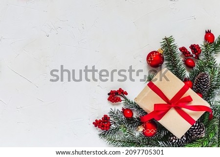 Christmas light background. Corner decorated with fir twigs and Christmas baubles. Red berries, candies, gifts, snowflake and fir cone. Top flat view with text copy-space.