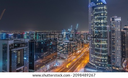 Dubai's business bay office towers aerial night timelapse with traffic. Rooftop view of some skyscrapers and new towers under construction