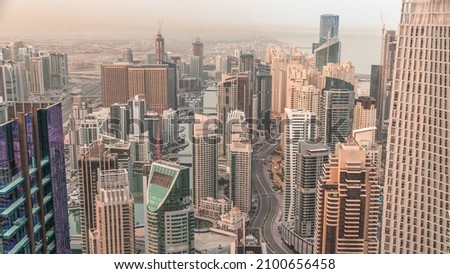 Skyline panoramic view of Dubai Marina showing an artificial canal surrounded by skyscrapers along shoreline aerial timelapse at morning during sunrise. Floating yachts and boats. DUBAI, UAE