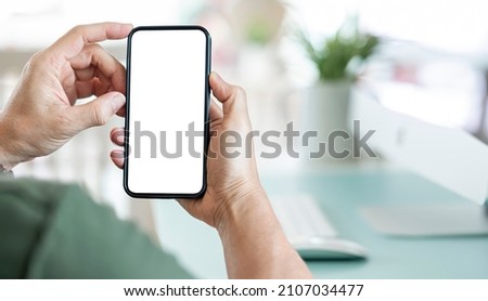 Closeup view of asian man holding in hands smartphone with empty blank mockup screen for advertising, using mobile apps. Remote e learning, online work, e commerce.