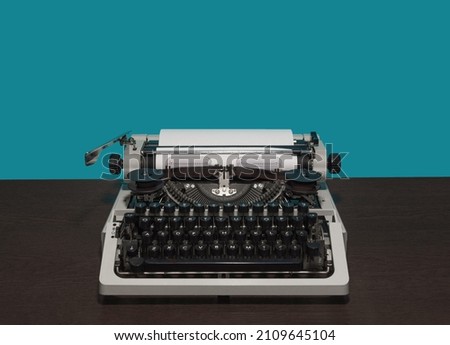 typewriter 70s without top cover on wood table and blue background