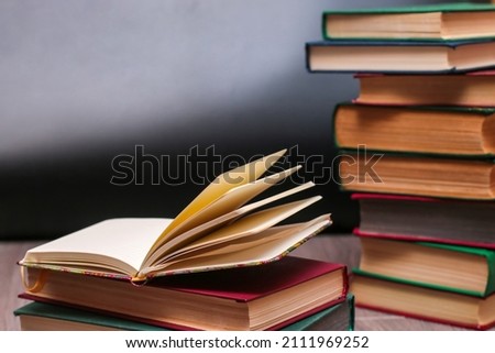 an open notepad lies on a pile of books against the background of a school board