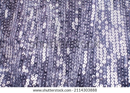 Texture of silver shiny sequins. Fashionable bright fabric with sequins. Selective focus.