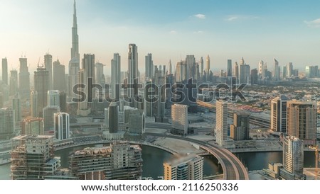 Panoramic skyline of Dubai with business bay and downtown district timelapse at evening before sunset. Aerial view of many modern skyscrapers. United Arab Emirates.