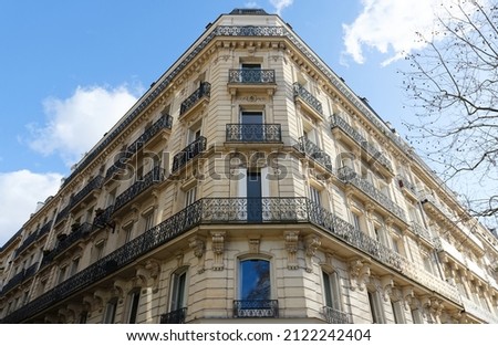 The flower-decked facade of traditional French house with typical balconies and windows. Paris.