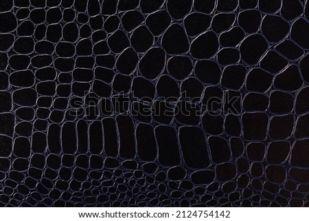 Texture of leatherette imitating of crocodile leather appearance dyed in black, fragment of the leather product close-up, background 
