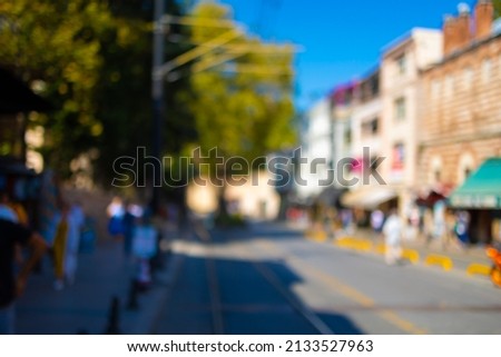 Blur texture background for design. Out of focus views of city streets on a sunny summer day. Buildings and roads, sky and trees, cars and people.