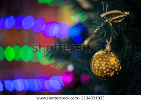Golden Christmas ball on the Christmas tree against the background of multi-colored bokeh.