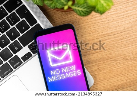 Concept waiting for a new message, closeup. Smartphone screen with no new messages notification, business workplace wooden table with laptop, top view photo