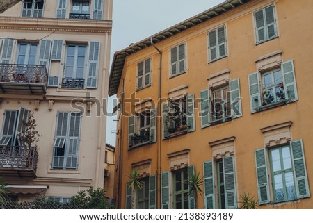 Exterior of a traditional residential buildings in Nice, France, plants on the windows.