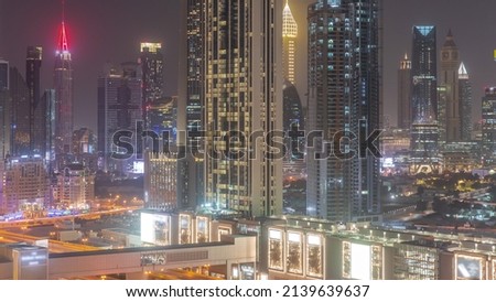 Row of the tall buildings around Sheikh Zayed Road and DIFC district aerial night timelapse in Dubai, UAE. International Financial Centre skyscrapers with glass surface