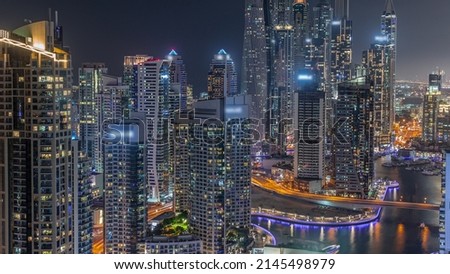 View of various skyscrapers in tallest recidential block in Dubai Marina aerial night timelapse with artificial canal. Many towers with glowing windows and yachts
