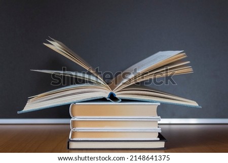 Collection of new books on a wooden brown table. Hardback books with dark background. A pile of school equipment ready to be read. Stack of wisdom. Educate yourself concept with copy space.