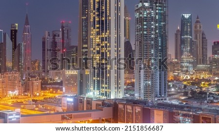 Panorama of tall buildings around Sheikh Zayed Road and DIFC district aerial night to day transition in Dubai, UAE. International Financial Centre skyscrapers with glass surface before sunrise