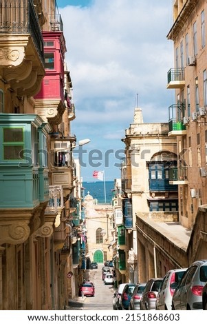 Typical Maltese street with balconies and blue windows on a clear day.
