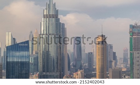 Skyscrapers rising above Dubai downtown timelapse, mall and finansial center surrounded by modern buildings aerial top view with cloudy sky