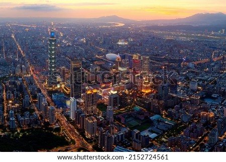 Aerial view of Taipei at dusk, the capital city of Taiwan, with 101 Tower standing out in Xinyi Commercial District, ovoid shaped Taipei Dome in nearby area and Tamsui River winding under golden sky