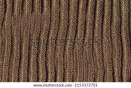 Sandy colored cozy sweater knitted made of natural wool texture. Warm pale brown knitted wool background.