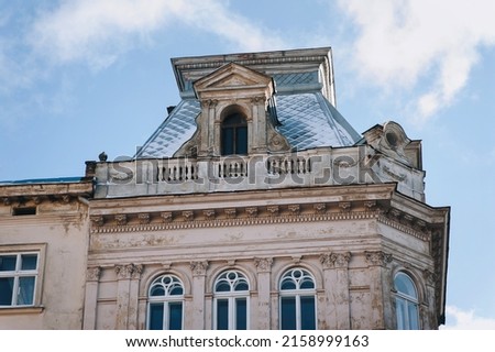 Snow-covered roof of an old European house in the neoclassical style with decor on the eaves and attic windows. Lvov, Ukraine.