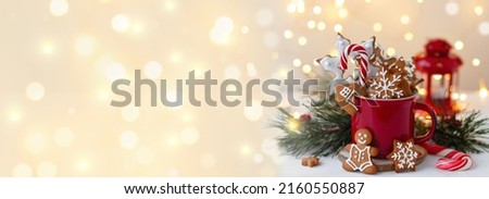 Christmas composition with gingerbread cookies, candy cane and marshmallow in a red mug. Cozy home atmosphere, delicious sweet holiday dessert. Traditional spices: cinnamon, anise. Banner, copy space