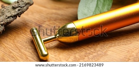 Face massage roller on wooden background, closeup