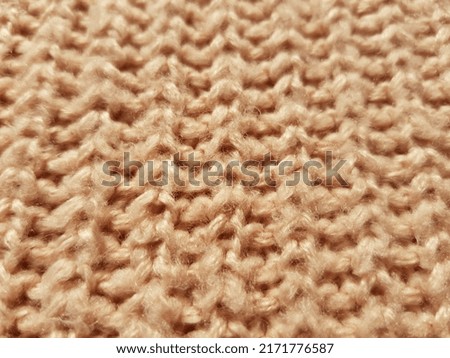 Light beige knitted fabric with a pattern is an English elastic band (macro, vertical, machine knit, texture).