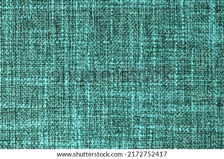 Close-up texture of natural turquoise coarse weave fabric or cloth. Fabric texture of natural cotton or linen textile material. Blue canvas background. Decorative fabric for upholstery furniture walls