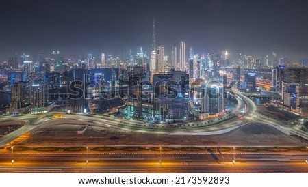 Panoramic skyline of Dubai with business bay and downtown district night. Aerial view of many modern skyscrapers with construction site and busy traffic on al khail road. United Arab Emirates.