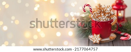 Christmas composition with gingerbread cookies, candy cane and marshmallow in a red mug. Cozy home atmosphere, delicious sweet holiday dessert. Traditional spices: cinnamon, anise. Banner, copy space