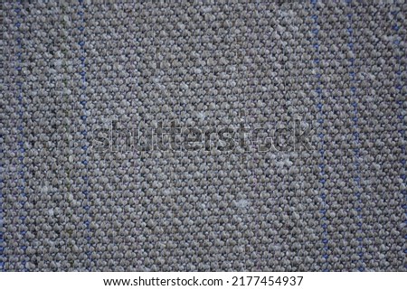 The reverse side of a multi-colored rug, which is a canvas with a white base and horizontal rows of fluffy wool squares of brown, beige, pink and purple colors. Textile background for the design.