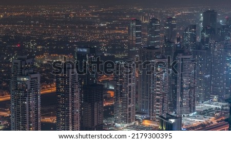 JLT skyscrapers near Sheikh Zayed Road night aerial timelapse. Residential illuminated buildings and traffic on highway