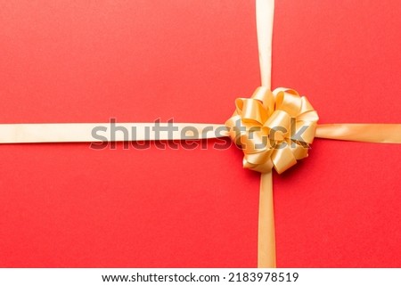 Top view of gold ribbon rolled and yellowbow isolated on colored background. Flat lay with copy space.