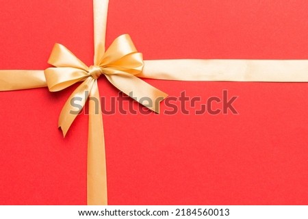 Top view of gold ribbon rolled and yellowbow isolated on colored background. Flat lay with copy space.