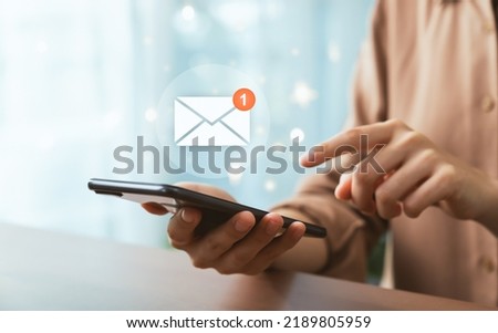 Hand holding smartphone and shows a digital screen of new email notifications.