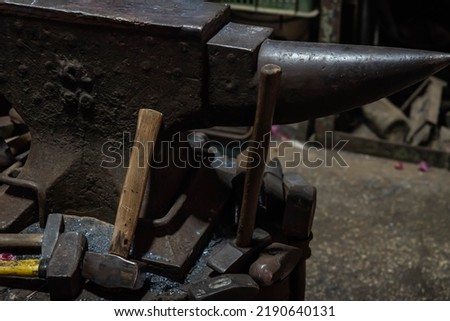 Heated metal and anvil. Blacksmith in the production process of other metal products handmade in the forge. Metalworker in motion forging metal with a hammer into knife. Metal craft industry 
