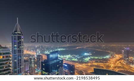 Aerial skyline with Golf Club, hotels and residential areas far away in desert in Dubai during all night timelapse with fog, UAE, top view from Dubai marina skyscrapers. Lights turning off