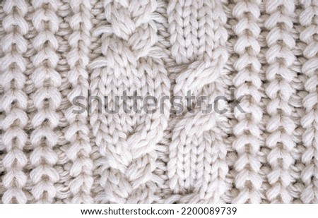 White knitted carpet closeup. Textile texture on white background. Detailed warm yarn backgrounds. Knit cashmere, beige wool. Natural woolen fabric, sweater fragment.