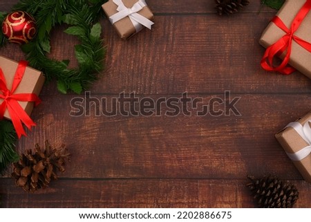 Top view of Christmas gift boxes, fir tree branches and pine cones on wooden background. Christmas background concept
