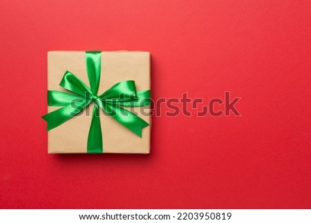 Gift box with green ribbon bow on color background, top view.