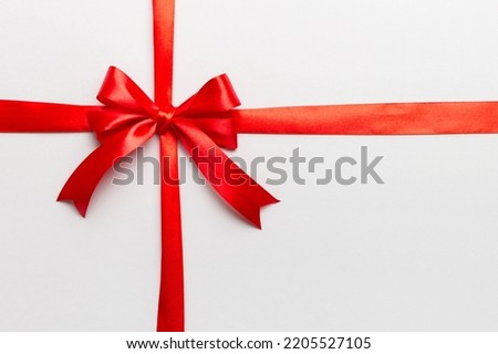 Top view of Red ribbon rolled and red bow isolated on colored background. Flat lay with copy space.