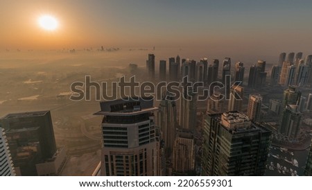 Panorama of Dubai Marina with JLT skyscrapers and golf course during sunrise timelapse, Dubai, United Arab Emirates. Aerial view from above towers foggy morning. City skyline with orange sky